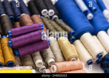 Multi-colored sewing threads laid out in a row. Bright background. Stock Photo
