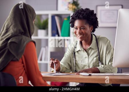 Female Doctor Or Consultant Having Meeting With Female Patient Wearing Headscarf To Discuss Scans Stock Photo
