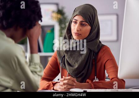 Female Doctor Or Consultant Wearing Headscarf Having Meeting With Unhappy Female Patient Stock Photo