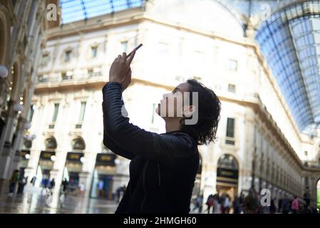 Beautiful young Asian female taking photos in the city centre of Milan Stock Photo