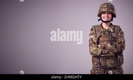 Studio Portrait Of Serious Young Female Soldier In Military Uniform Against  Plain Background Stock Photo