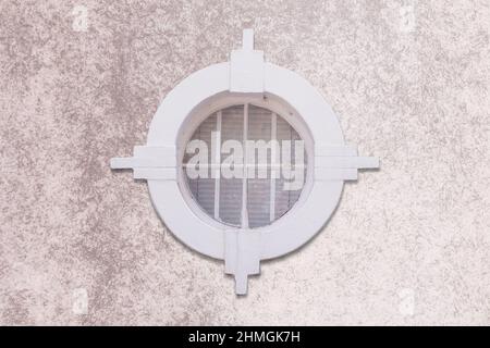 Round and vintage wooden window on brick wall. White Round window on grunge paint brick wall. Background of old white vintage brick wall and window. A Stock Photo