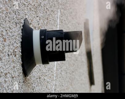 Steaming central heating boiler vent on an external house wall Stock Photo