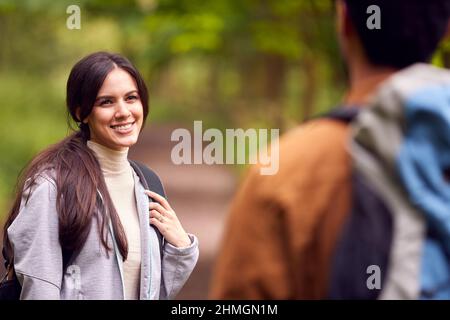 Couple With Backpacks Hiking Along Path Through Trees In Countryside Together Stock Photo