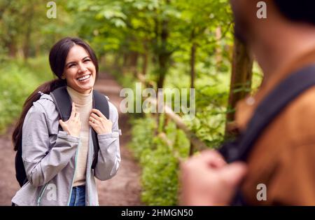Couple With Backpacks Hiking Along Path Through Trees In Countryside Together Stock Photo