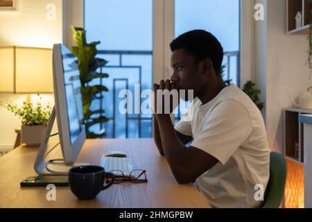 Pensive freelance programmer thoughtful work on application software or website serious look at pc Stock Photo