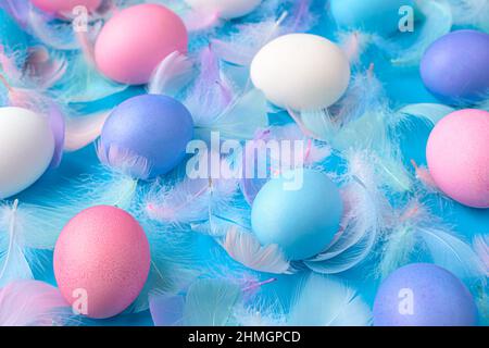 Colored Easter eggs and feathers on a blue background close-up. Happy Easter concept, close-up. Stock Photo