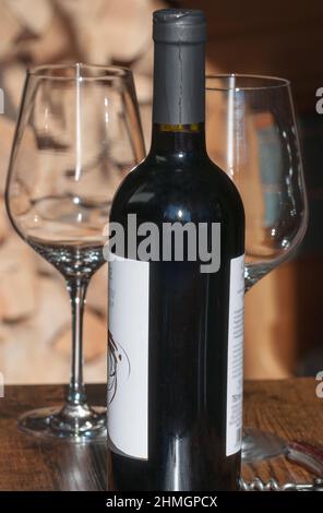 bottle of italian red wine with goblets resting on a wooden table Stock Photo