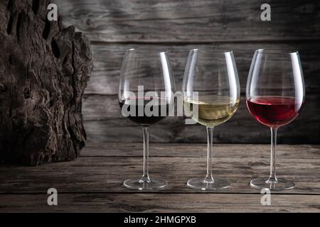 Red, white and rose wine in wine glasses on dark wood background. Beverage and wine concept. Stock Photo