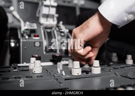 cropped view of pilot using switcher on control panel in airplane Stock Photo