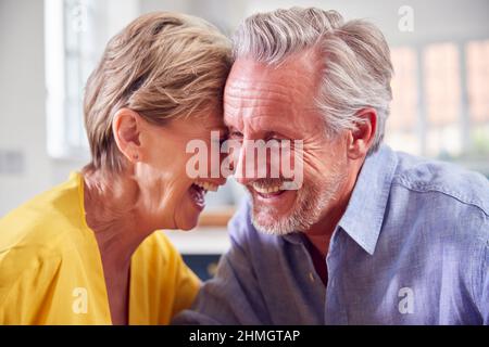 Loving Retired Couple Sitting Around Table At Home Together Stock Photo