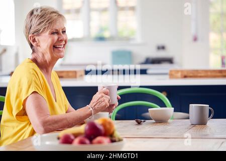 Senior Woman Sitting Around Table At Home Having Healthy Breakfast Stock Photo