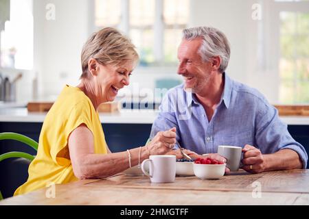Retired Couple Sitting Around Table At Home Having Healthy Breakfast Together Stock Photo