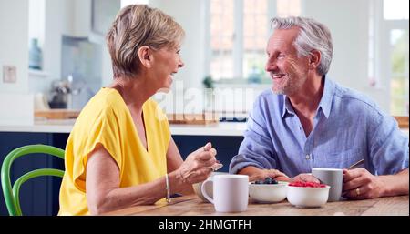 Retired Couple Sitting Around Table At Home Having Healthy Breakfast Together Stock Photo