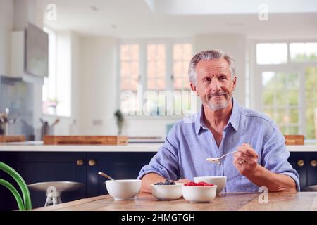 Senior Man Sitting Around Table At Home Having Healthy Breakfast Stock Photo