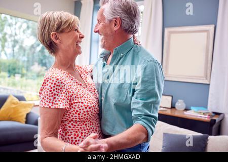 Romantic Senior Retired Couple Dancing In Lounge At Home Together Stock Photo