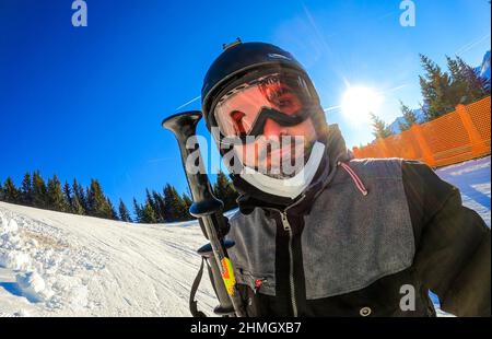 Portrait of man enjoying winter vacations taking selfie in skiing gear. Person on skiing vacation dressed in skiing gear with helmets and ski goggles Stock Photo