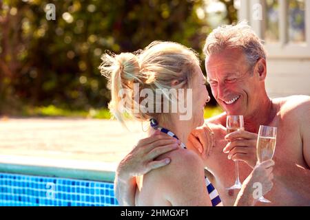 Loving Mature Couple Relaxing In Swimming Pool On Summer Vacation Celebrating Drinking Champagne Stock Photo