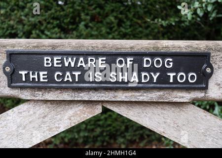 Beware of dog sign, the cat is shady too. Quirky amusing sign on a gate. Stock Photo