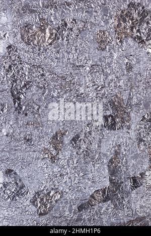 Shiny heavily wrinkled metal silver gray foil vertical texture background for design Stock Photo