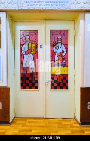 Gallery door featuring painted stained glass looking local archetype people. A doctor with a lung X-Ray and a doctor, nurse examining a child. At the Stock Photo