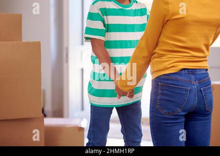 Close Up Of Brother And Sister Holding Hands Standing In Hallway Of New Home Stock Photo