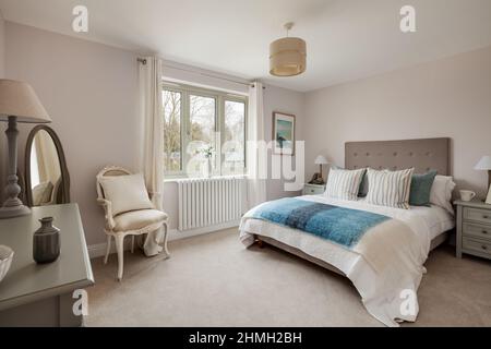 Newport, Essex - March 21 2019: Luxury modern bedroom within vacant staged new home with bedspread in blue and white and green side tables. Stock Photo