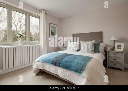 Newport, Essex - March 21 2019: Dressed bed within new house bedroom with bkue and white bedspread, matching pillows and furnishings Stock Photo