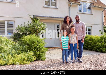 Portrait Of Smiling Family Standing Outside Home Together Stock Photo