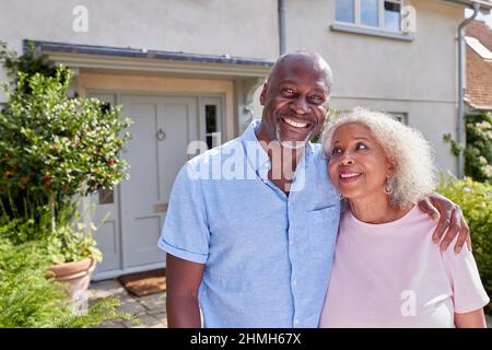 Portrait Of Smiling Senior Couple Standing Outside Home Together Stock Photo