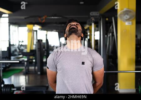young man busy doing neck rotation warm up exercise at gym - concept of wellness, healthy lifestyle and work out session Stock Photo