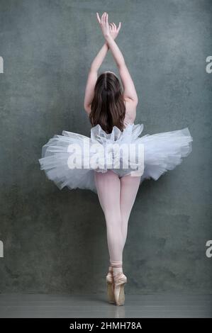 Ballerina in white tutu and pointe shoes with long brown hair flowing Stock Photo
