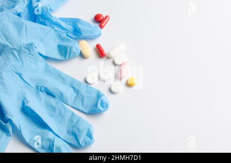 Medical gloves white colored tablets and pills on blue background closeup Stock Photo