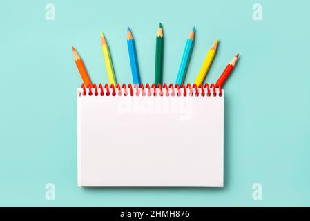 Spiral notebook with colored pencils and with copy space for your image or text over blue background Stock Photo