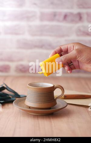 young man putting artificial sweetener in tea, Stock Photo