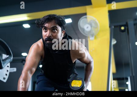young man busy exercising using dumbells at fitness center - concept of burning fat, bodybuilding and workout center Stock Photo