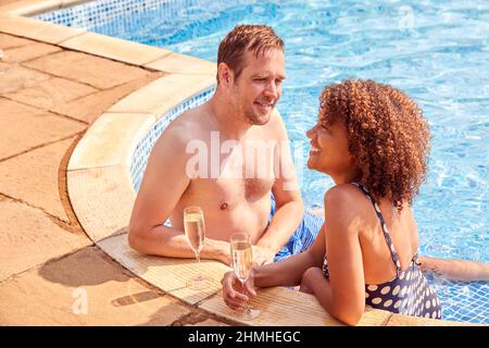 Romantic Couple Drinking Champagne In Swimming Pool On Vacation Stock Photo