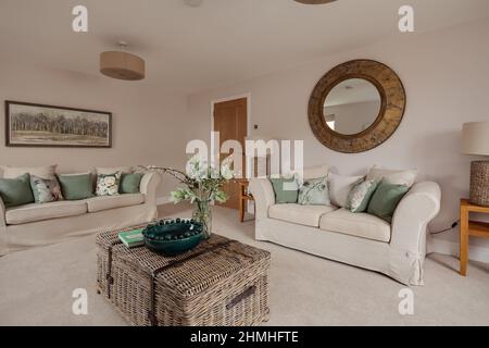 Newport, Essex - March 21 2019: Luxury modern living room in brand new staged home with chic stylish furniture and patterned cushions. Stock Photo