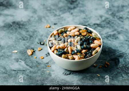 a bowl with some roasted soya beans of different colors, served as a snack, on a veined storne surface Stock Photo