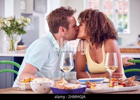 Kissing Couple Having Romantic Meal At Home On Date Night Together Stock Photo