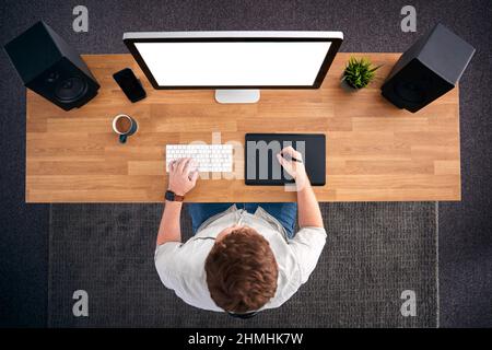 Overhead View Of Male Graphic Designer Working At Computer In Creative Office Stock Photo