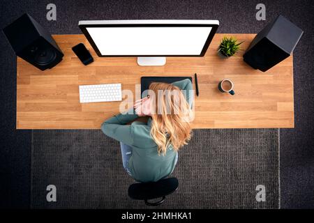 Overhead View Of Tired Female Graphic Designer At Computer Sleeping On Desk Stock Photo