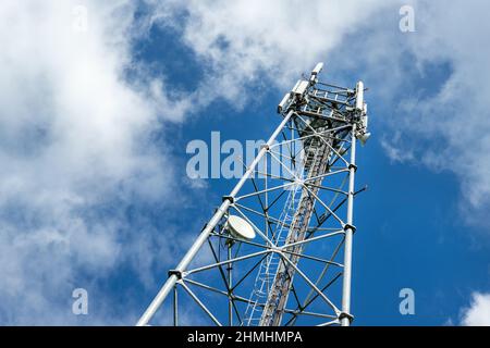 Bottom perspective pov of modern metal steel mobile 5g network wireless telecom tower against clear blue sky background on bright day. Microwave Stock Photo