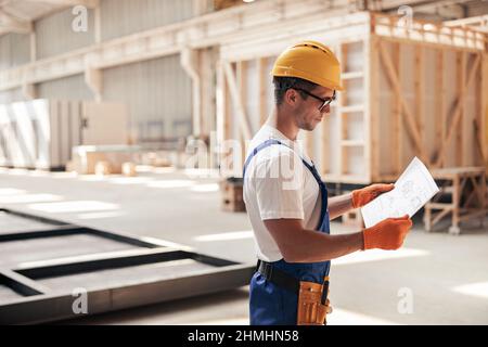 Male builder studying architectural plan at construction site Stock Photo