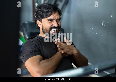 young man suffering from chest pain during weight lifting at gym - concept of injury,risk of heart attack due to intense workout and Healthcare Stock Photo