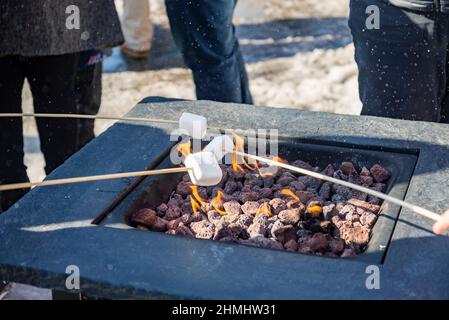 A marshmallow on a stick being roasted over a camping fire Stock Photo
