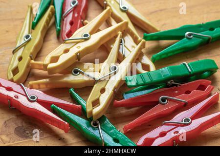 Different classic clothespins made of plastic from a surface with old light wooden structure table Stock Photo