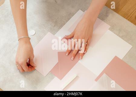 Cropped photo of woman hands making pink composition weeding invitation paper wrapping envelope, seal wax, papercraft. Stock Photo