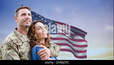 Smiling caucasian mid adult male soldier with caucasian young wife against us flag during sunset Stock Photo