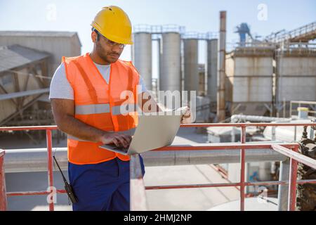 Multiethnic engineer working with laptop at plant Stock Photo